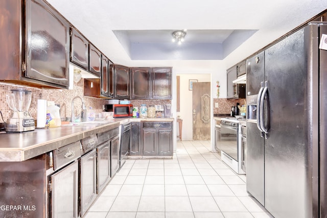 11625 Soberana Ln Unit A & B, El Paso, TX 79936 - kitchen featuring appliances with stainless steel finishes, light tile patterned floors, a raised ceiling, decorative backsplash, and under cabinet range hood