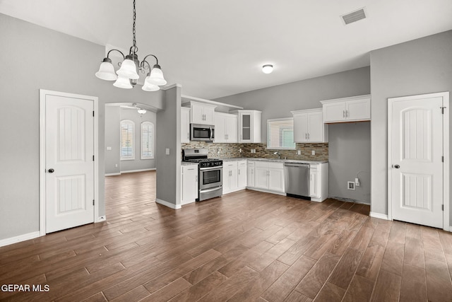 13519 Hazlewood St, El Paso, TX 79928 - kitchen featuring stainless steel appliances, arched walkways, white cabinetry, a chandelier, and dark wood-style flooring