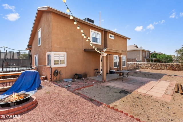 1328 Morgan Marie St, El Paso, TX 79936 - rear view of house with an outdoor fire pit, a trampoline, a patio, stucco siding, and a fenced backyard