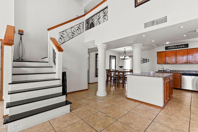 1328 Morgan Marie St, El Paso, TX 79936 - kitchen with stainless steel dishwasher, decorative columns, brown cabinets, light tile patterned floors, and a towering ceiling