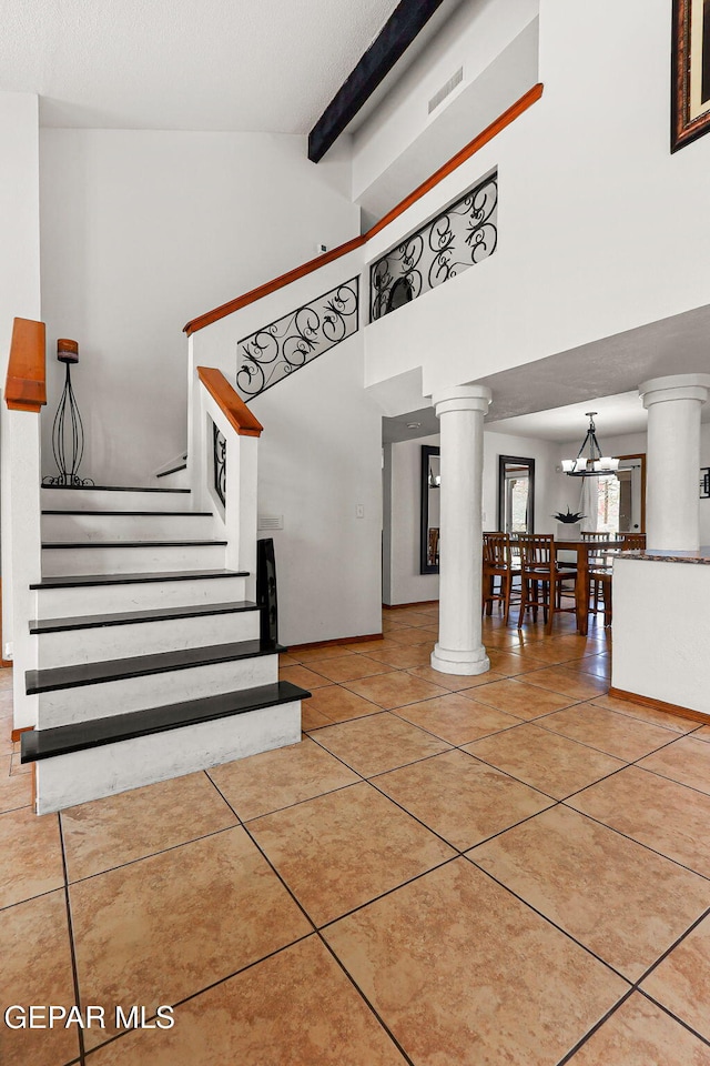1328 Morgan Marie St, El Paso, TX 79936 - stairway with decorative columns, tile patterned floors, a chandelier, high vaulted ceiling, and beamed ceiling
