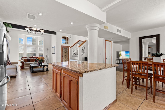 1328 Morgan Marie St, El Paso, TX 79936 - kitchen featuring ornate columns, stainless steel refrigerator with ice dispenser, a center island, open floor plan, and a textured ceiling