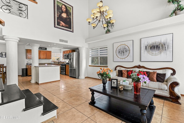 1328 Morgan Marie St, El Paso, TX 79936 - living room featuring ornate columns, light tile patterned floors, a towering ceiling, baseboards, and a chandelier