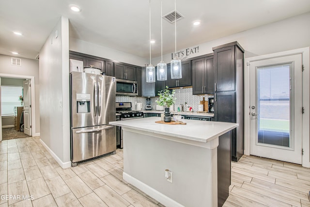 12826 Osmotherly Ave, El Paso, TX 79928 - kitchen with appliances with stainless steel finishes, light countertops, decorative backsplash, a kitchen island, and wood finish floors
