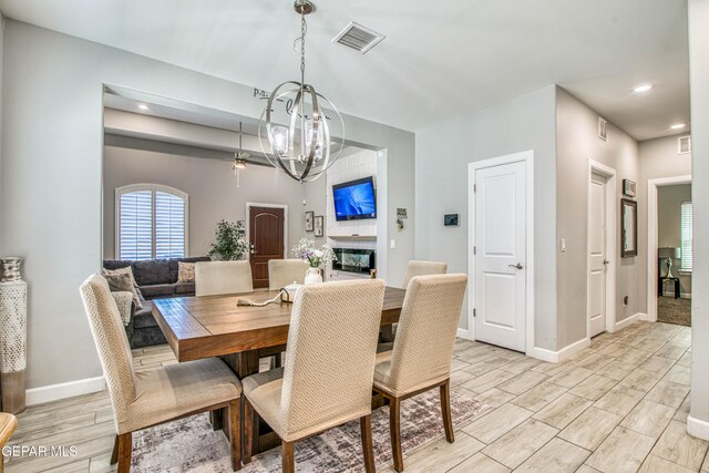 12826 Osmotherly Ave, El Paso, TX 79928 - dining room featuring a chandelier, wood tiled floors, recessed lighting, baseboards, and a glass covered fireplace