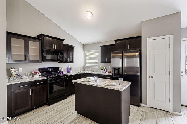 401 Gran Villa Pl, Socorro, TX 79927 - kitchen featuring black appliances, vaulted ceiling, a sink, light stone countertops, and glass insert cabinets