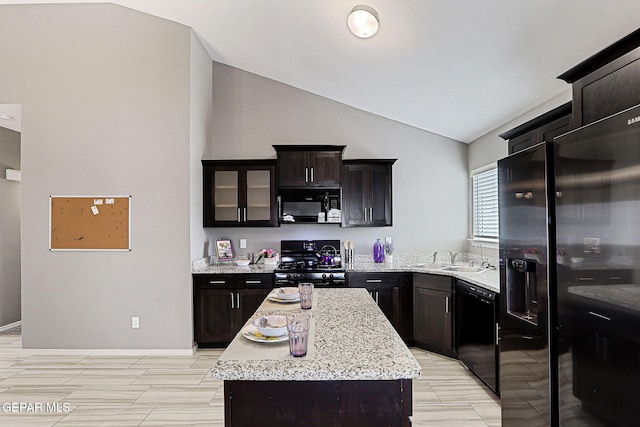 401 Gran Villa Pl, Socorro, TX 79927 - kitchen with black appliances, vaulted ceiling, a center island, a sink, and light stone counters