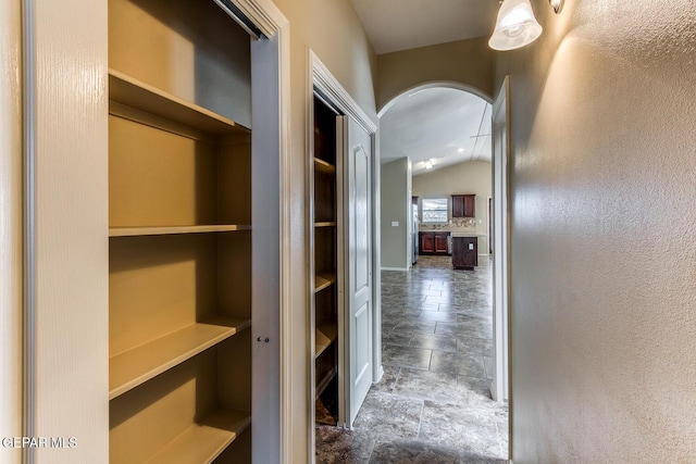2412 Escape Point St, El Paso, TX 79938 - hall with vaulted ceiling, arched walkways, stone finish flooring, a textured wall, and baseboards