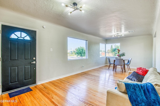 1401 N Boone St, El Paso, TX 79903 - entrance foyer with light wood finished floors, a textured ceiling, baseboards, and a chandelier