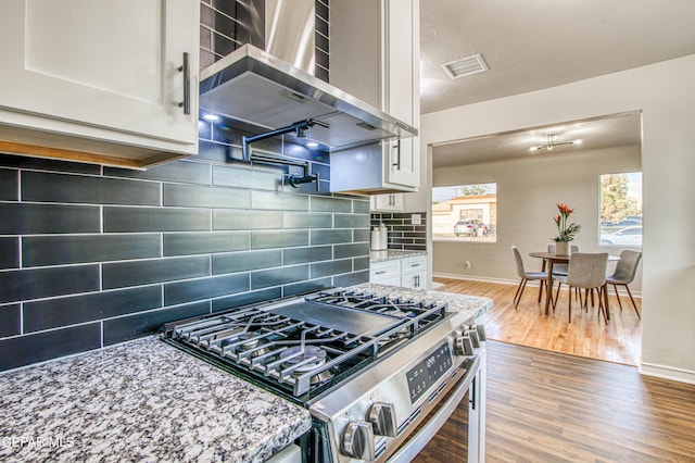 1401 N Boone St, El Paso, TX 79903 - kitchen featuring gas stove, wall chimney range hood, white cabinets, decorative backsplash, and wood finished floors