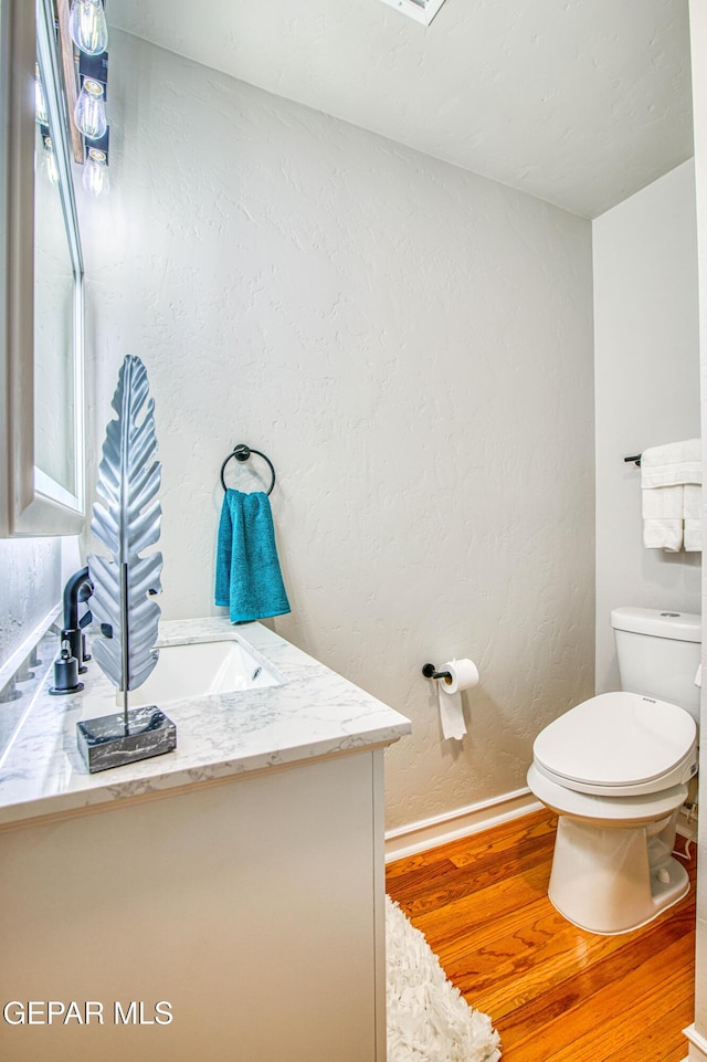 1401 N Boone St, El Paso, TX 79903 - half bathroom with vanity, wood finished floors, toilet, baseboards, and a textured wall