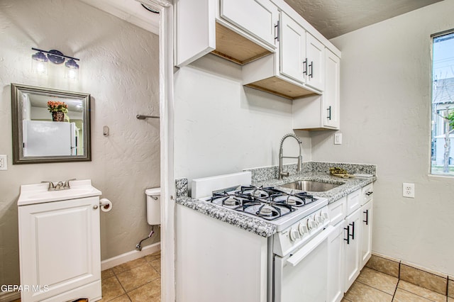 1401 N Boone St, El Paso, TX 79903 - kitchen featuring a sink, white gas stove, light tile patterned flooring, and white cabinetry