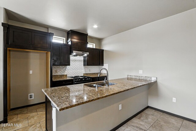 14425 Donny Murray Ln, Horizon City, TX 79928 - kitchen with a sink, under cabinet range hood, black gas range, a peninsula, and baseboards