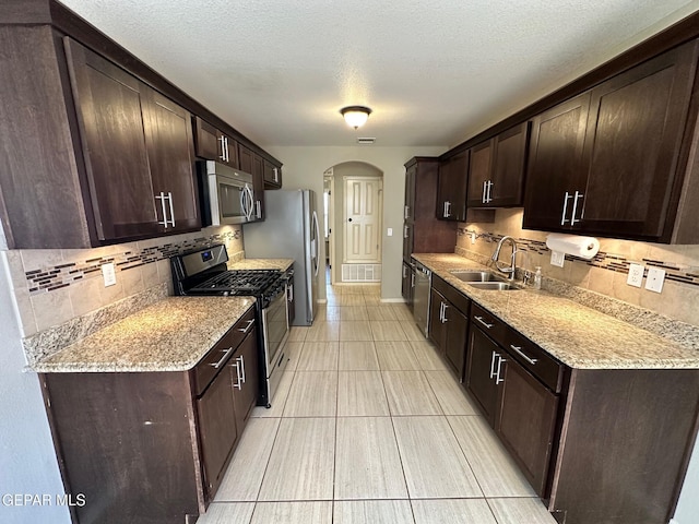 7217 Long Meadow Dr, El Paso, TX 79934 - kitchen with stainless steel appliances, a sink, arched walkways, tasteful backsplash, and dark brown cabinets