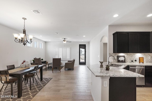3809 Plan Pl, El Paso, TX 79938 - kitchen with a sink, dishwasher, dark cabinetry, arched walkways, and backsplash