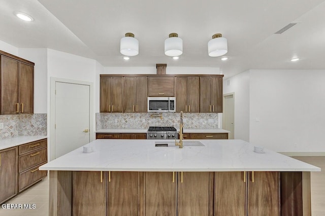 12748 Polo Norte Dr, El Paso, TX 79934 - kitchen featuring stainless steel microwave, decorative backsplash, recessed lighting, range, and light stone counters