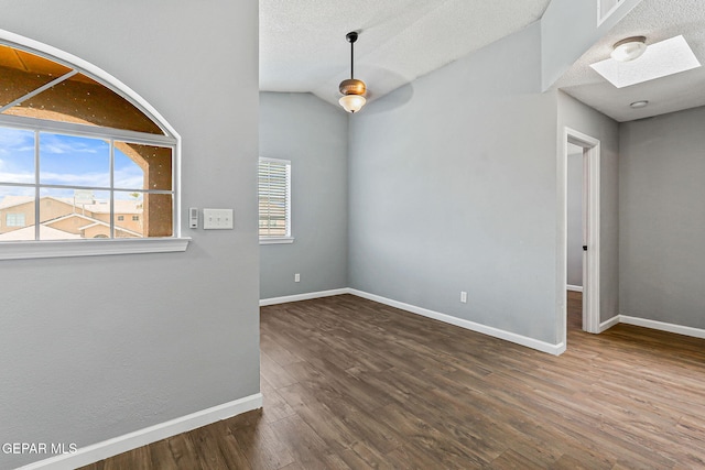 11912 Mesquite Miel Dr, El Paso, TX 79938 - spare room featuring a skylight, baseboards, wood finished floors, lofted ceiling, and a textured ceiling
