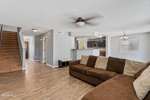 11912 Mesquite Miel Dr, El Paso, TX 79938 - living room featuring a chandelier, stairway, light wood-style floors, baseboards, and a textured ceiling