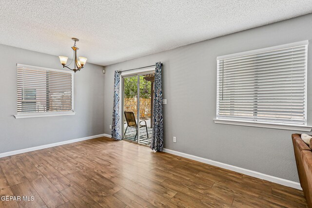 11912 Mesquite Miel Dr, El Paso, TX 79938 - spare room featuring a chandelier, wood finished floors, a textured ceiling, and baseboards