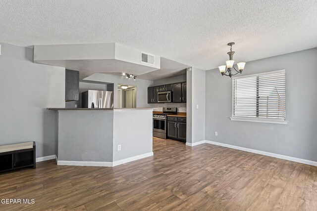 11912 Mesquite Miel Dr, El Paso, TX 79938 - kitchen with appliances with stainless steel finishes, a chandelier, a peninsula, dark wood-type flooring, and a textured ceiling