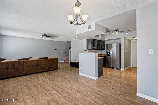 11912 Mesquite Miel Dr, El Paso, TX 79938 - unfurnished living room with a textured ceiling, stairway, ceiling fan, a chandelier, and light wood-style flooring