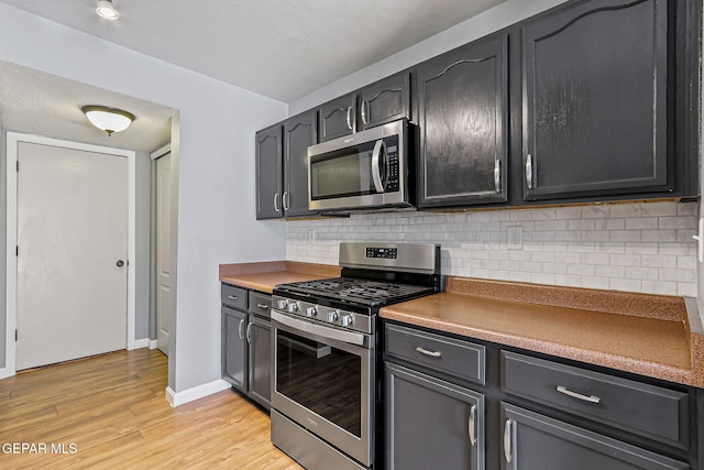 11912 Mesquite Miel Dr, El Paso, TX 79938 - kitchen featuring appliances with stainless steel finishes, light wood finished floors, tasteful backsplash, and baseboards