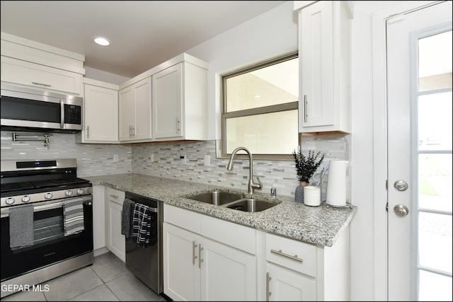 13106 Cleethorpes St, El Paso, TX 79928 - kitchen featuring appliances with stainless steel finishes, a sink, light tile patterned floors, decorative backsplash, and white cabinets