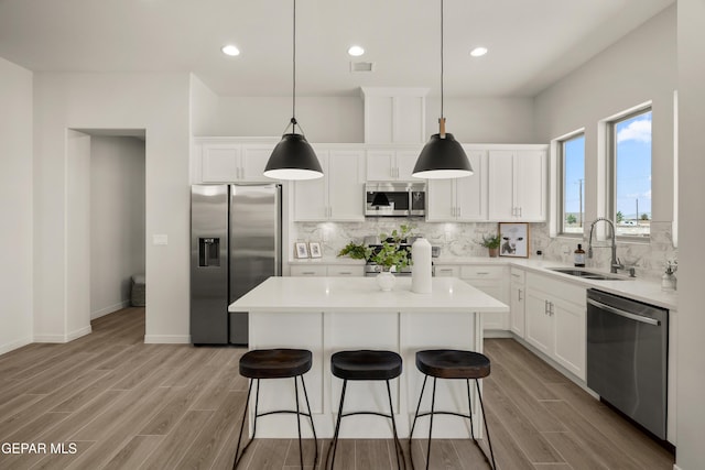 14932 Hill Ridge Ct, El Paso, TX 79938 - kitchen featuring stainless steel appliances, a sink, a center island, tasteful backsplash, and light wood-style floors
