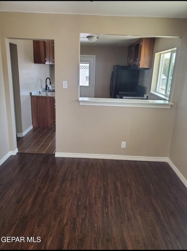 4943 Aiken Ln, El Paso, TX 79924 - unfurnished living room with dark wood-type flooring, baseboards, plenty of natural light, and a sink