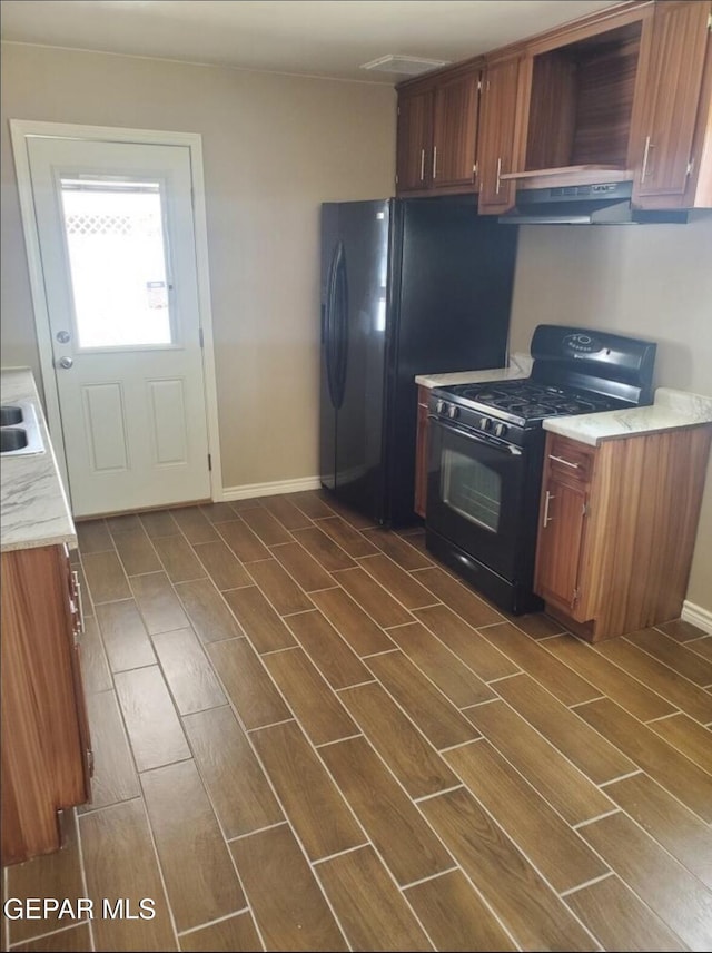 4943 Aiken Ln, El Paso, TX 79924 - kitchen with black gas stove, under cabinet range hood, light countertops, and baseboards