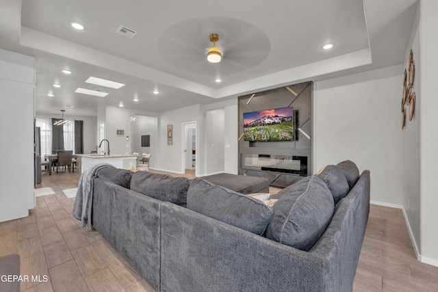 281 Farnborough St, Horizon City, TX 79928 - living area featuring a raised ceiling, a ceiling fan, recessed lighting, baseboards, and light wood-style floors