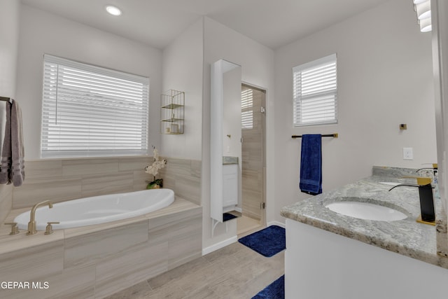 281 Farnborough St, Horizon City, TX 79928 - full bath with double vanity, a stall shower, a garden tub, wood finished floors, and baseboards
