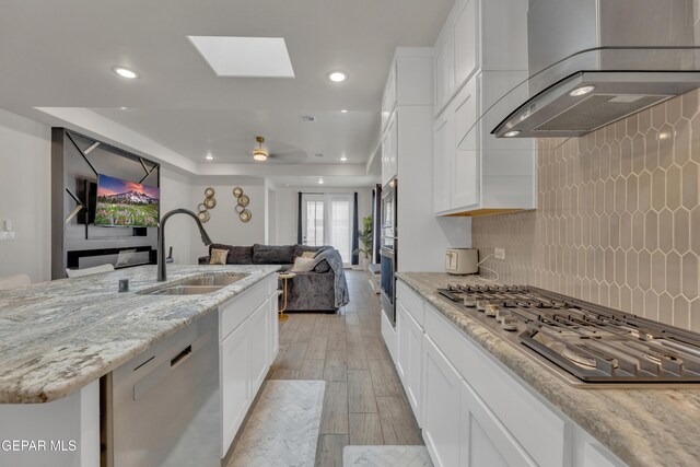 281 Farnborough St, Horizon City, TX 79928 - kitchen with appliances with stainless steel finishes, a sink, wall chimney exhaust hood, light wood-type flooring, and open floor plan
