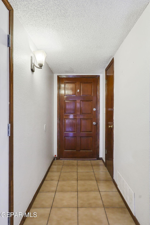 7721 Maya Ave, El Paso, TX 79912 - hallway featuring a textured ceiling, light tile patterned floors, and baseboards