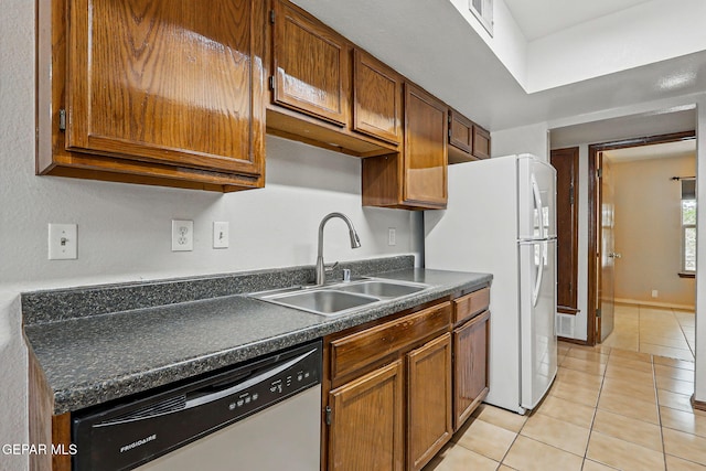 7721 Maya Ave, El Paso, TX 79912 - kitchen featuring dishwasher, a sink, light tile patterned floors, dark countertops, and freestanding refrigerator