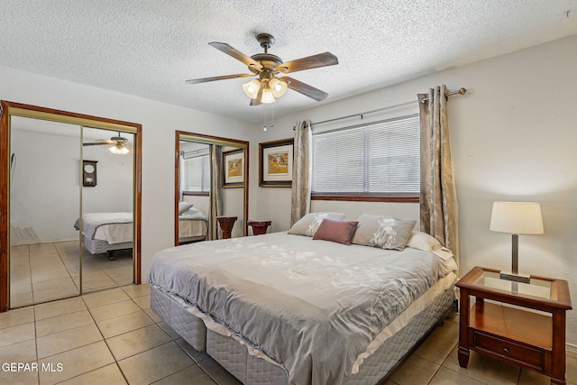 7721 Maya Ave, El Paso, TX 79912 - bedroom with multiple closets, light tile patterned floors, a textured ceiling, and a ceiling fan