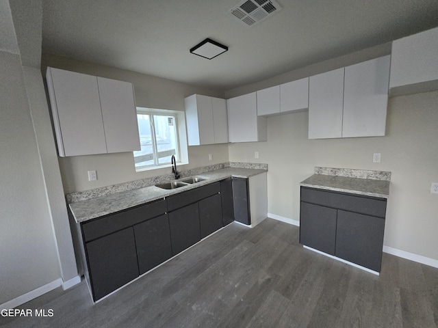 2917 Mobile Ave, El Paso, TX 79930 - kitchen featuring a sink, dark wood-style floors, baseboards, white cabinetry, and light countertops