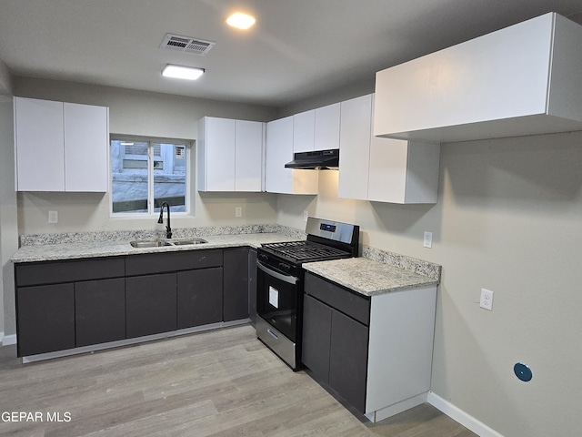 2917 Mobile Ave, El Paso, TX 79930 - kitchen with stainless steel gas stove, under cabinet range hood, white cabinets, light wood-style floors, and light stone counters
