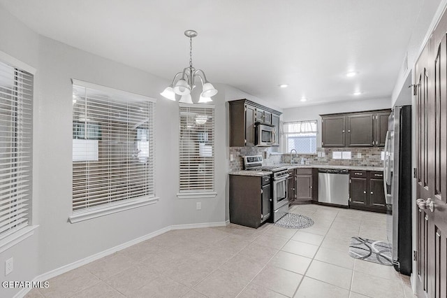 5429 Santiago Roque Dr, El Paso, TX 79934 - kitchen with appliances with stainless steel finishes, a chandelier, dark brown cabinetry, backsplash, and light tile patterned floors