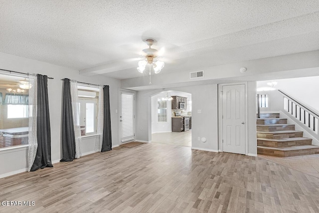 5429 Santiago Roque Dr, El Paso, TX 79934 - unfurnished living room featuring a chandelier, a textured ceiling, light wood-style floors, arched walkways, and a ceiling fan