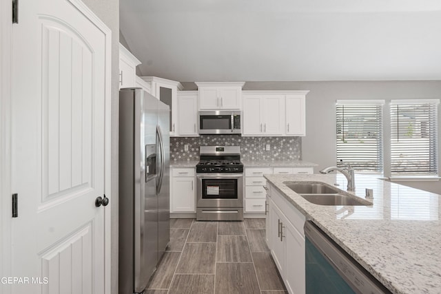 1329 Madero Ave, El Paso, TX 79928 - kitchen featuring stainless steel appliances, a sink, white cabinetry, backsplash, and light stone countertops