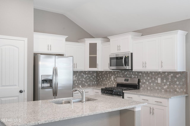 1329 Madero Ave, El Paso, TX 79928 - kitchen with stainless steel appliances, a sink, vaulted ceiling, decorative backsplash, and white cabinets