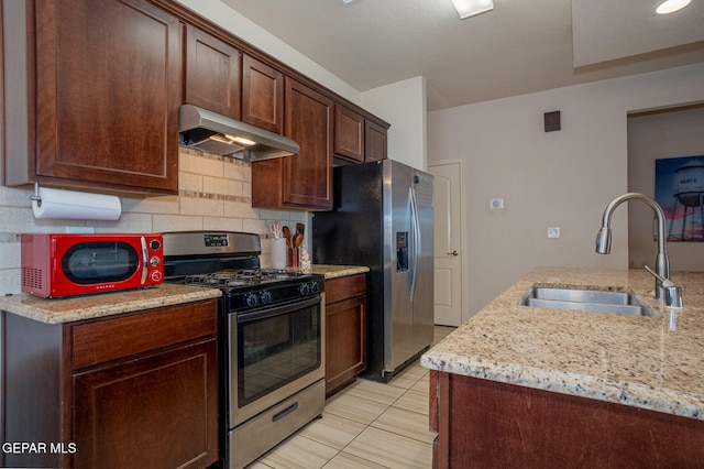 1916 William Caples St, El Paso, TX 79938 - kitchen with under cabinet range hood, stainless steel appliances, a sink, tasteful backsplash, and light stone counters