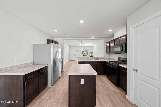 14573 Banana Yucca Ave, Horizon City, TX 79928 - kitchen with black appliances, a sink, dark brown cabinets, light wood-style flooring, and light countertops