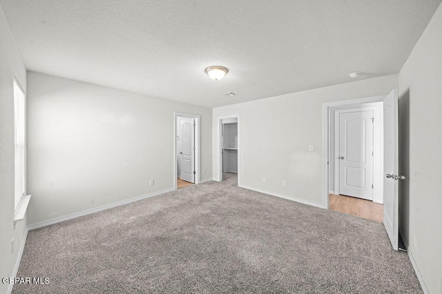 14573 Banana Yucca Ave, Horizon City, TX 79928 - unfurnished bedroom featuring light carpet, baseboards, a textured ceiling, and a walk in closet
