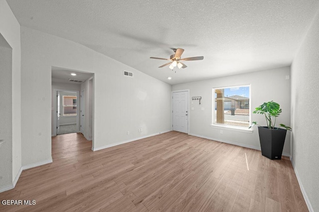 14573 Banana Yucca Ave, Horizon City, TX 79928 - unfurnished living room featuring ceiling fan, light wood-style floors, baseboards, lofted ceiling, and a textured ceiling