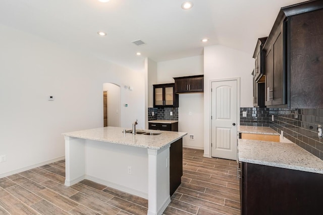 13852 Summer Wave Ave, El Paso, TX 79928 - kitchen with a sink, arched walkways, backsplash, wood tiled floors, and a center island with sink
