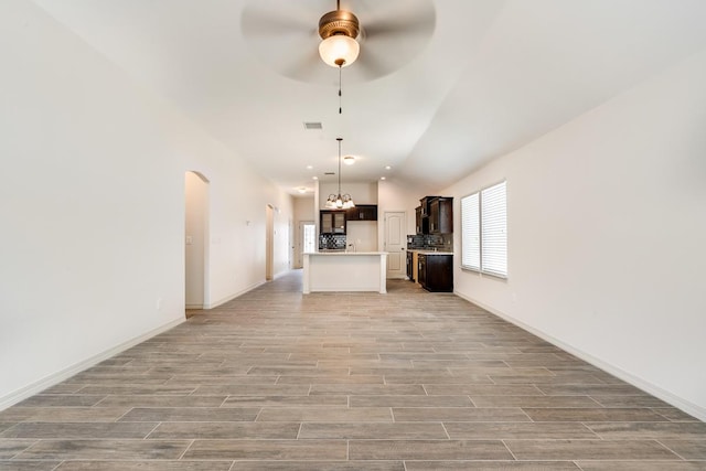 13852 Summer Wave Ave, El Paso, TX 79928 - unfurnished living room featuring ceiling fan, light wood finished floors, lofted ceiling, arched walkways, and baseboards