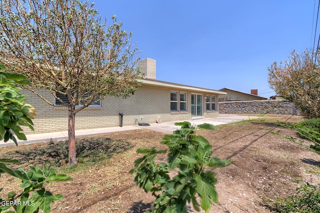 5814 Beaumont Pl, El Paso, TX 79912 - rear view of property featuring brick siding, a chimney, and a patio