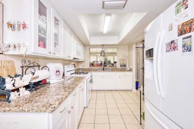 10605 Park View Cir, El Paso, TX 79935 - kitchen featuring white appliances, light tile patterned flooring, white cabinetry, glass insert cabinets, and a raised ceiling